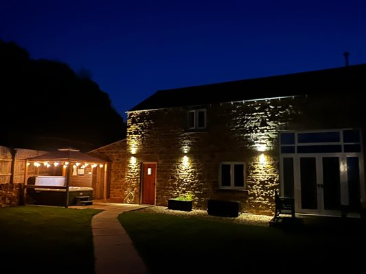 the barn at night from the garden, the hot tub and the building are lit up